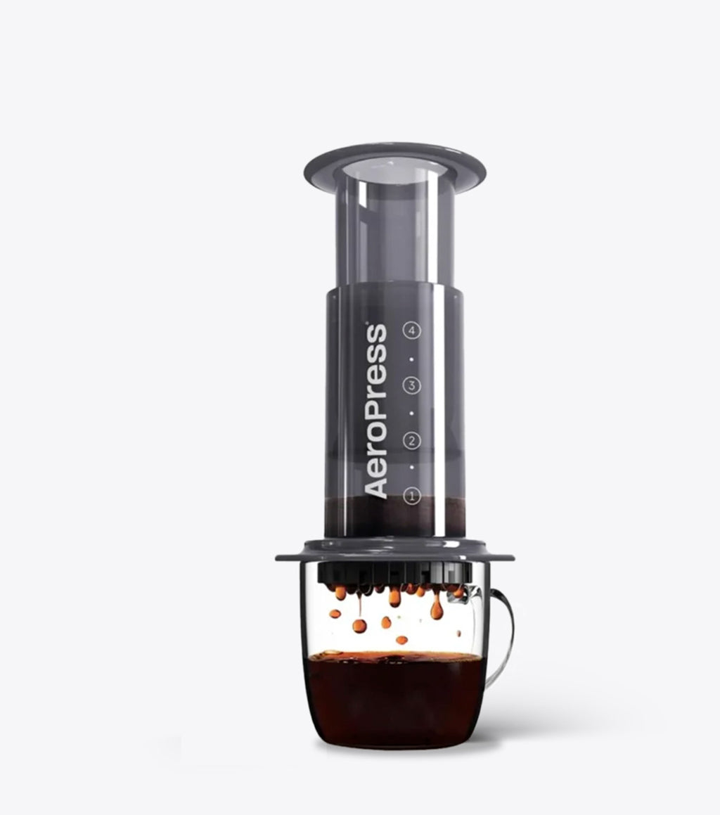 AeroPress coffee maker with a glass container of coffee on a white background